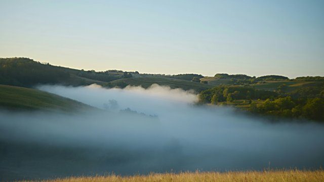 Fog filling valley green hills